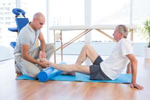 Trainer working with man on exercise mat in fitness studio