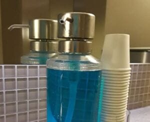 Blue mouthwash in dispenser with cups
