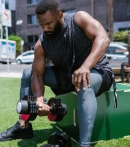 Man curling adjustable dumbbell in park