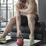 man lifting weights with sore muscle - need rest time between workouts