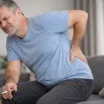 Middle age man getting up from sofa with pain